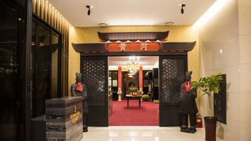 Una entrada tradicional china con alfombra roja, un candelabro y dos estatuas.