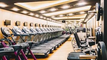 A gym with multiple treadmills lined up on one side and various weightlifting equipment on the other.