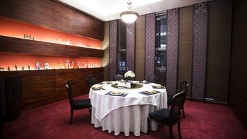 A round table with a white tablecloth, surrounded by chairs, in a room with a red carpet and wooden paneling.