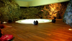 A room with a stone wall, wooden floor, and a circular light fixture. - Résidence La Marina (Trois-Ilets)