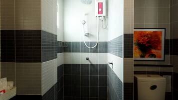 A bathroom with a shower, toilet, and a framed picture on the wall.
