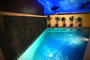 Een buitenzwembad, ligstoelen bij het zwembad