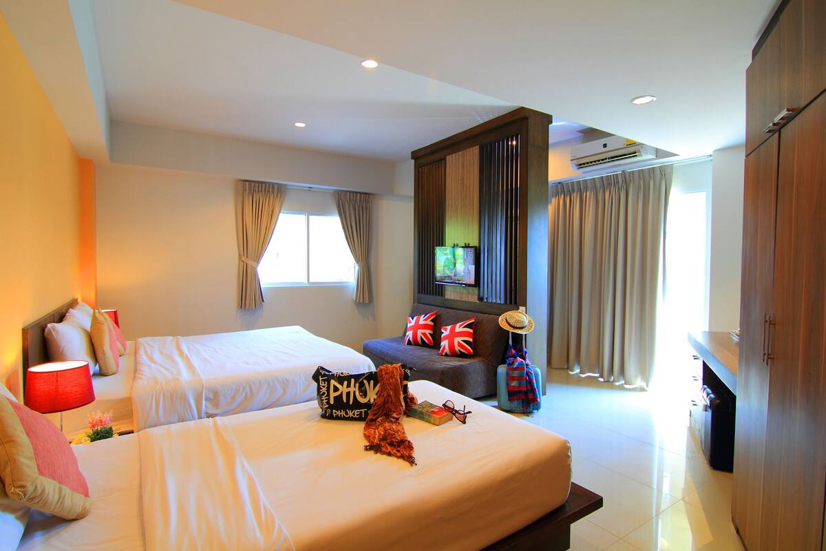 A hotel room with two beds, a TV, a wardrobe, and a window with curtains.