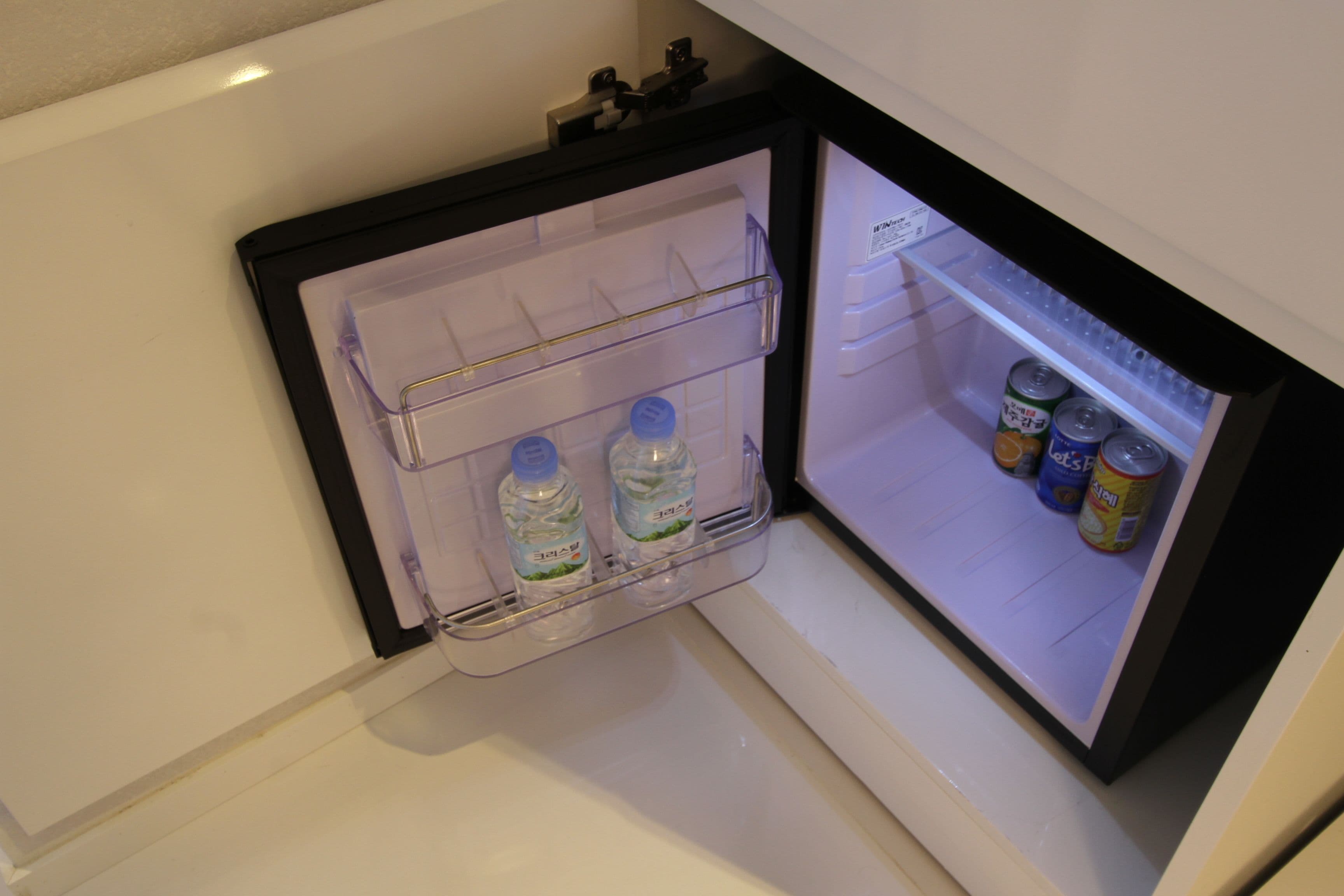 A mini-fridge with two water bottles and several cans.