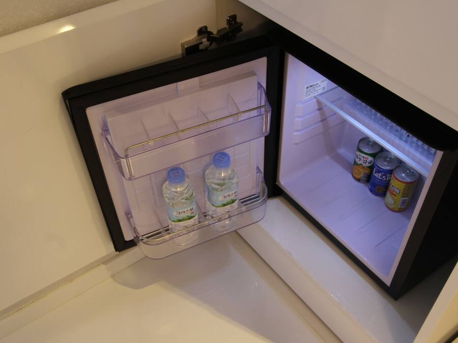 A mini-fridge with two water bottles and several cans.