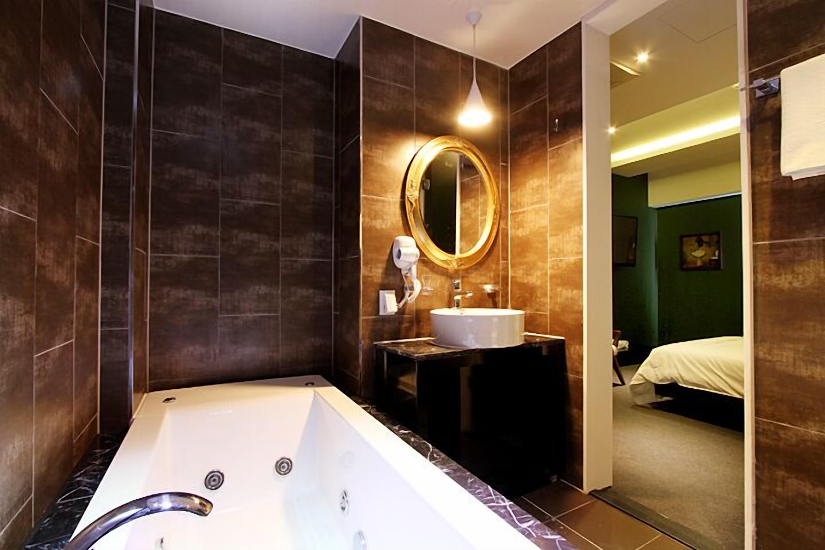 A modern bathroom with a large bathtub, a round mirror, and a sink.