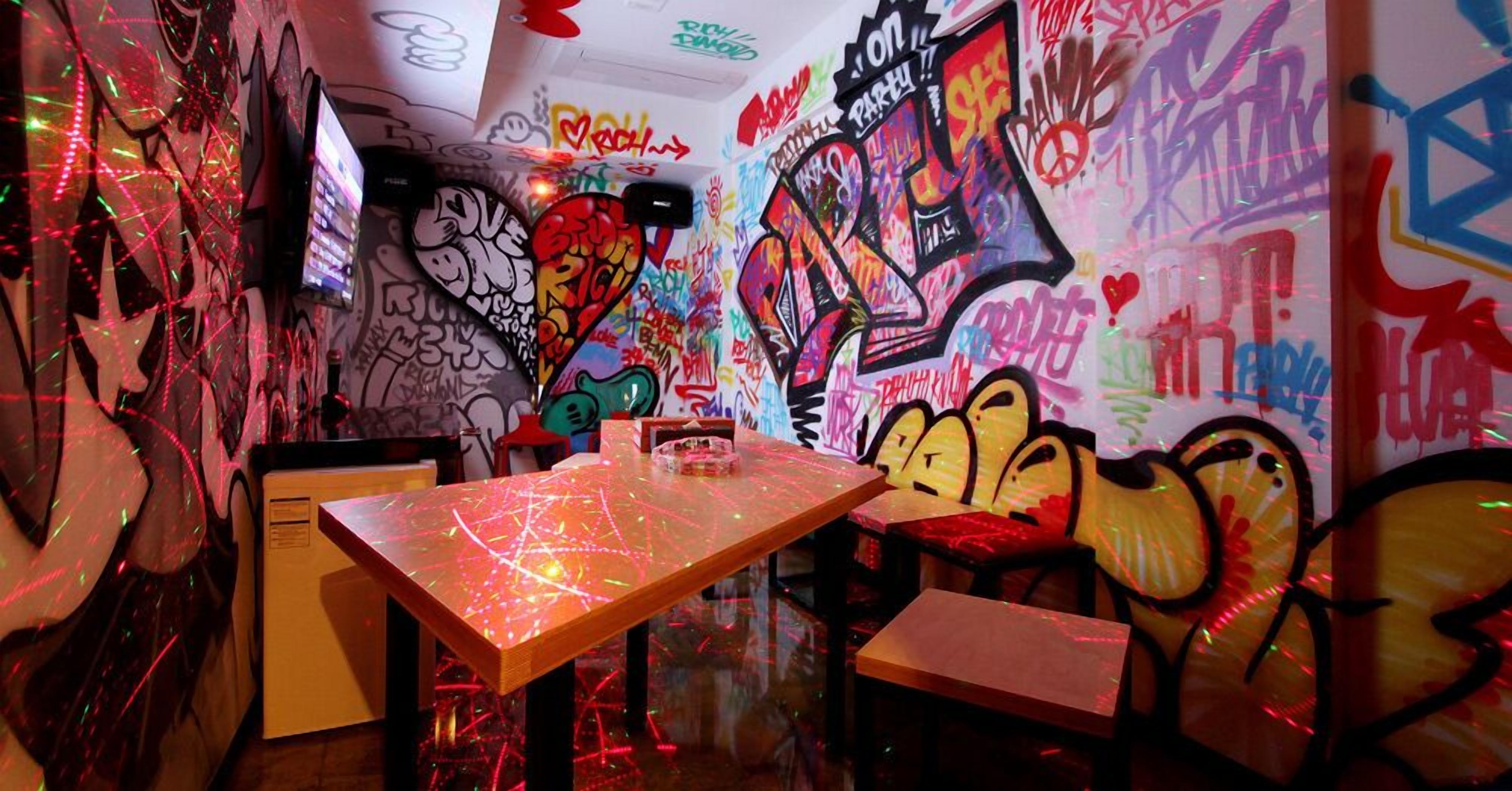 Een kamer met muren en tafels vol graffiti, met een mix van kleurrijke en abstracte ontwerpen.