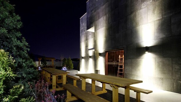 An outdoor patio area with wooden tables and benches, surrounded by greenery. - Rich Diamond Hotel (Seoul)