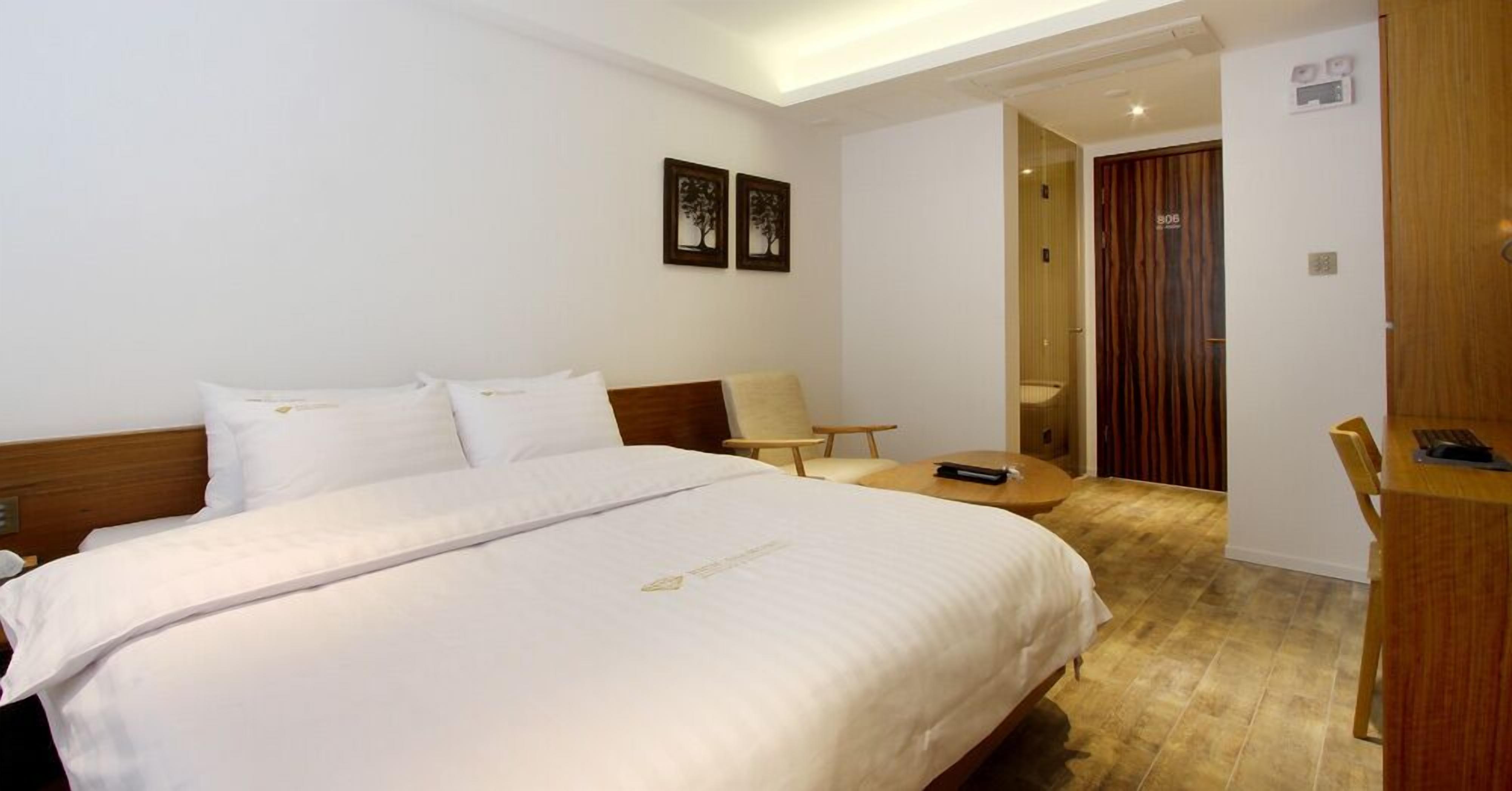 Una habitación de hotel con una cama grande, un escritorio, una silla y una mesita.