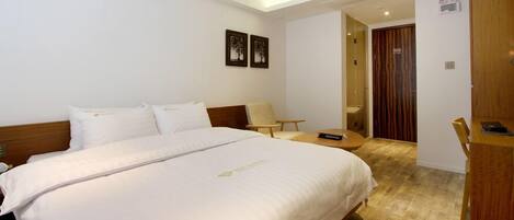 Una habitación de hotel con una cama grande, un escritorio, una silla y una mesita.