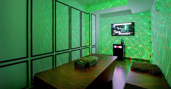Una habitación con una mesa larga, un televisor de pantalla plana montado en la pared y una pared con un diseño luminoso geométrico.