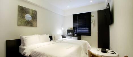 Una habitación de hotel con cama, escritorio, silla, televisor y ventana con persianas.