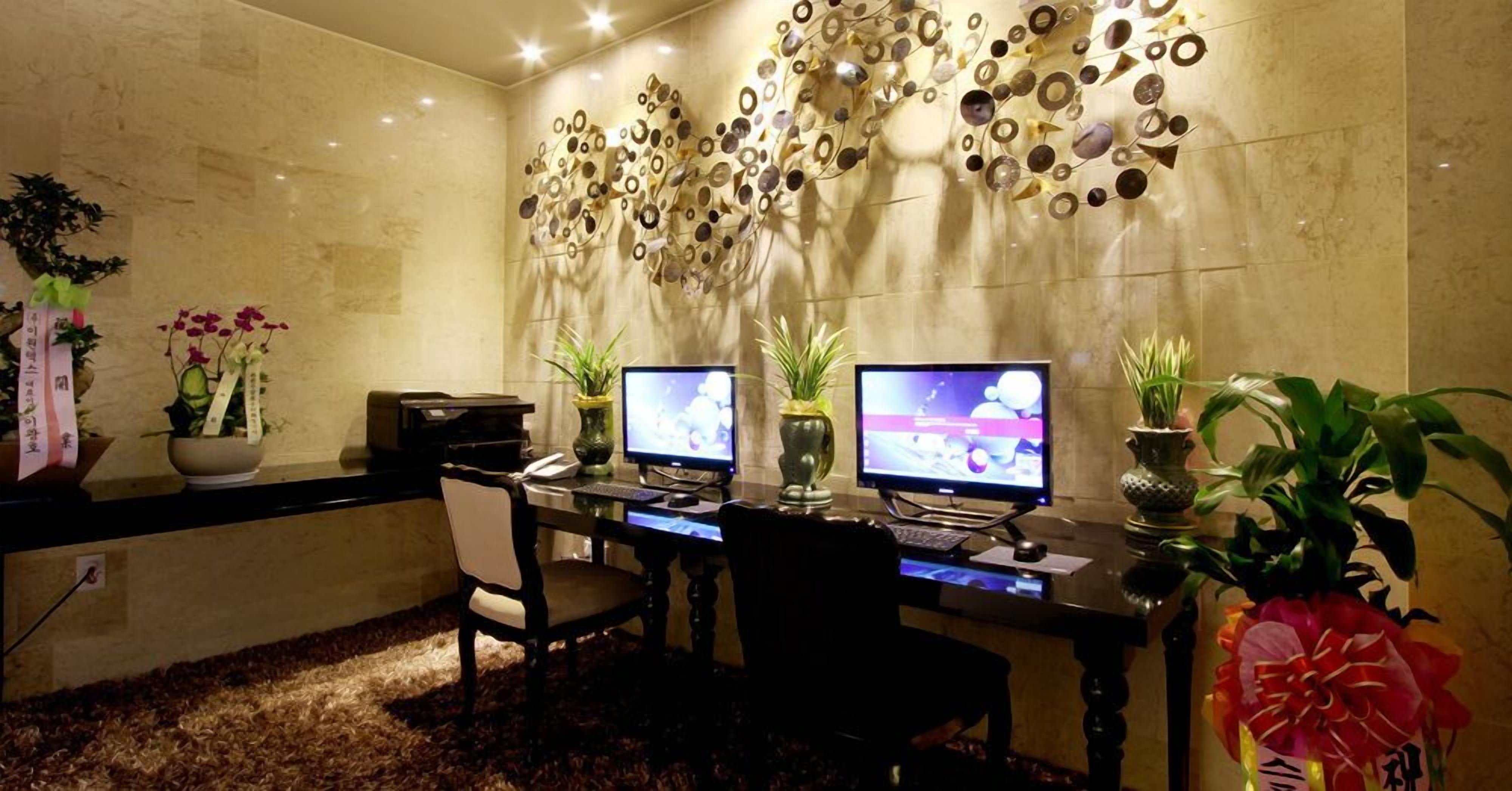A modern office space with two desks, computers, and decorative wall art.