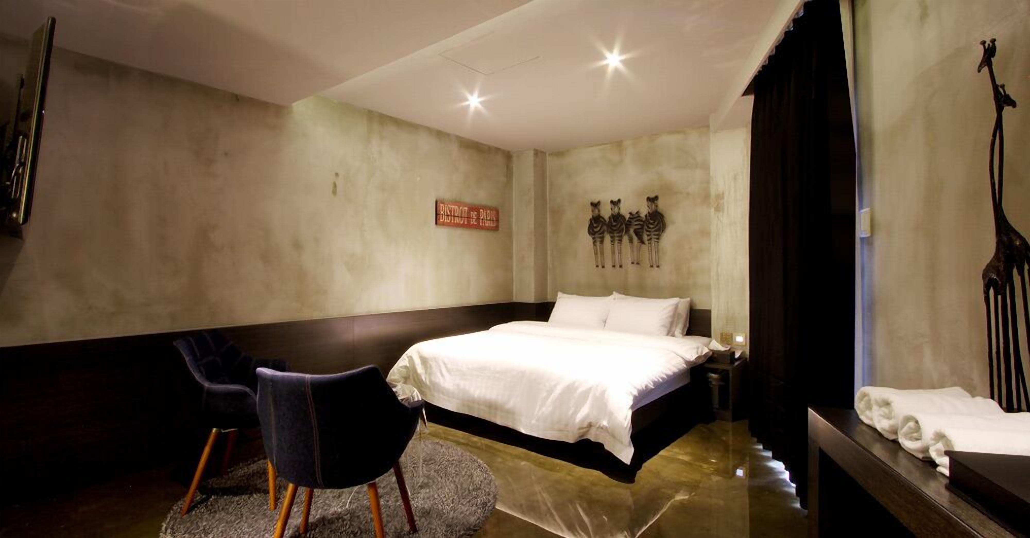Un dormitorio con cama, una silla, un adorno de cebra en la pared y un cartel.