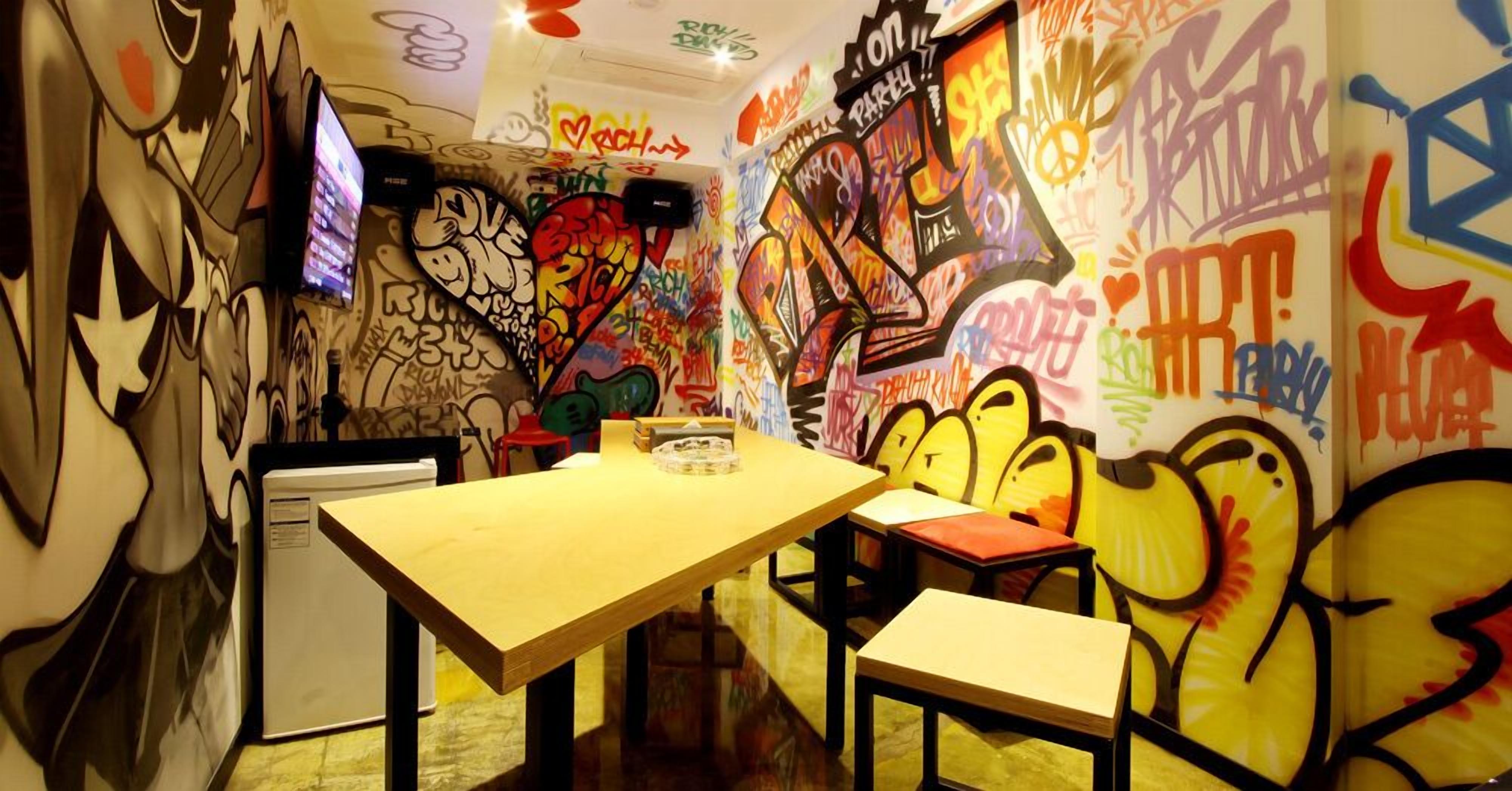 A restaurant interior with graffiti-covered walls, wooden tables, and chairs.