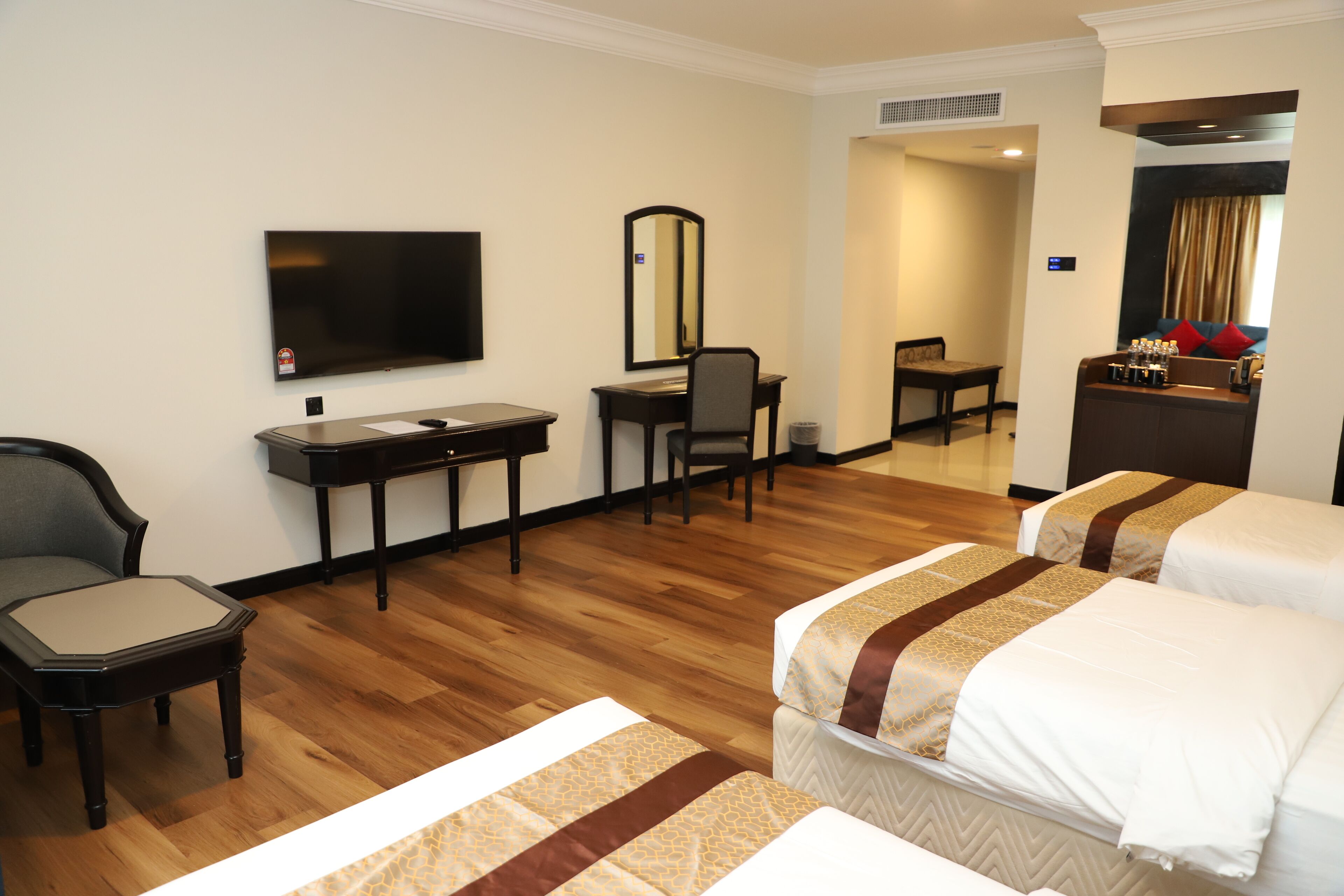 A hotel room with two beds, a desk, a chair, a television, and a mirror.