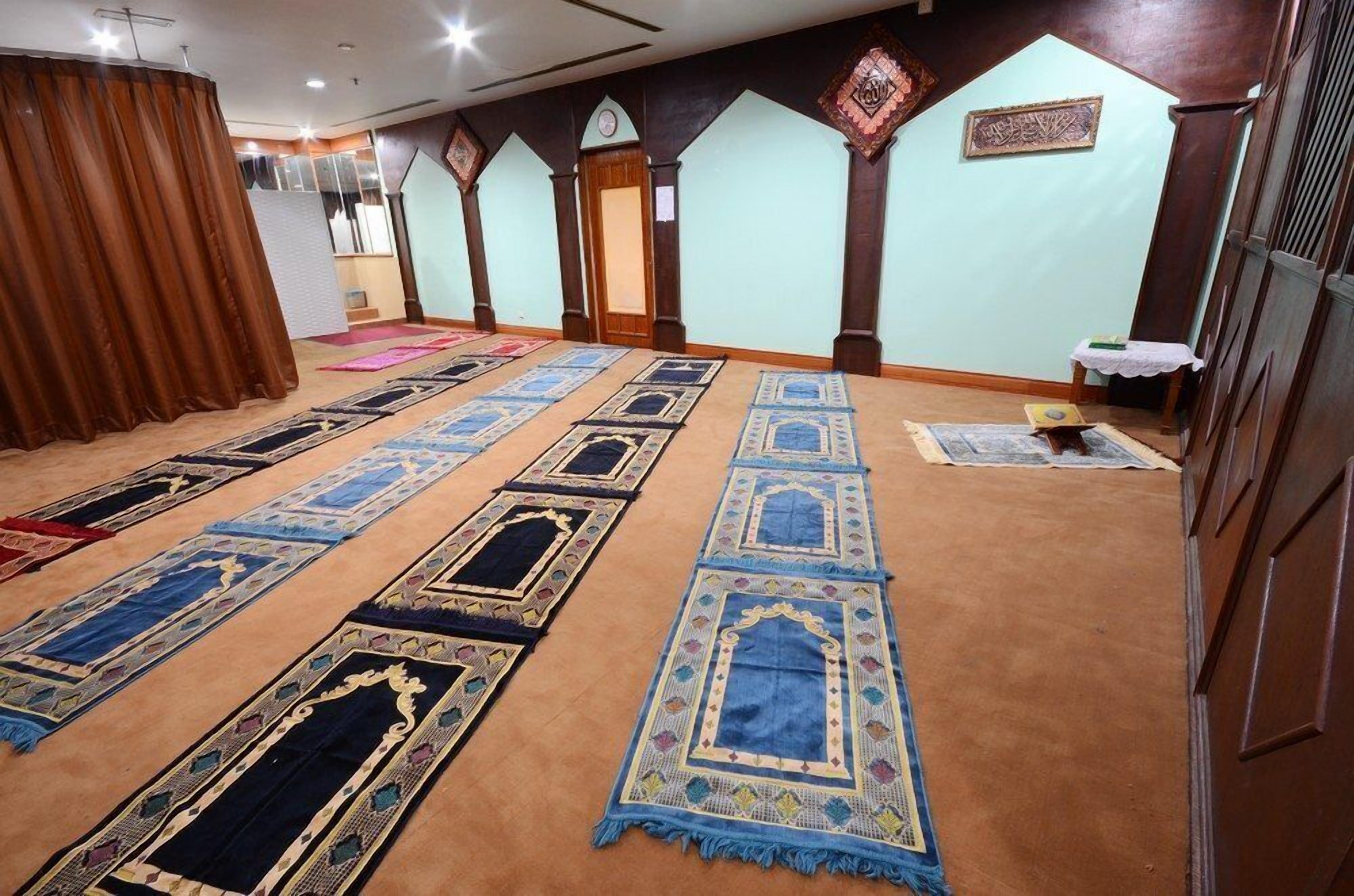 A prayer hall with rows of prayer mats and wooden pillars.