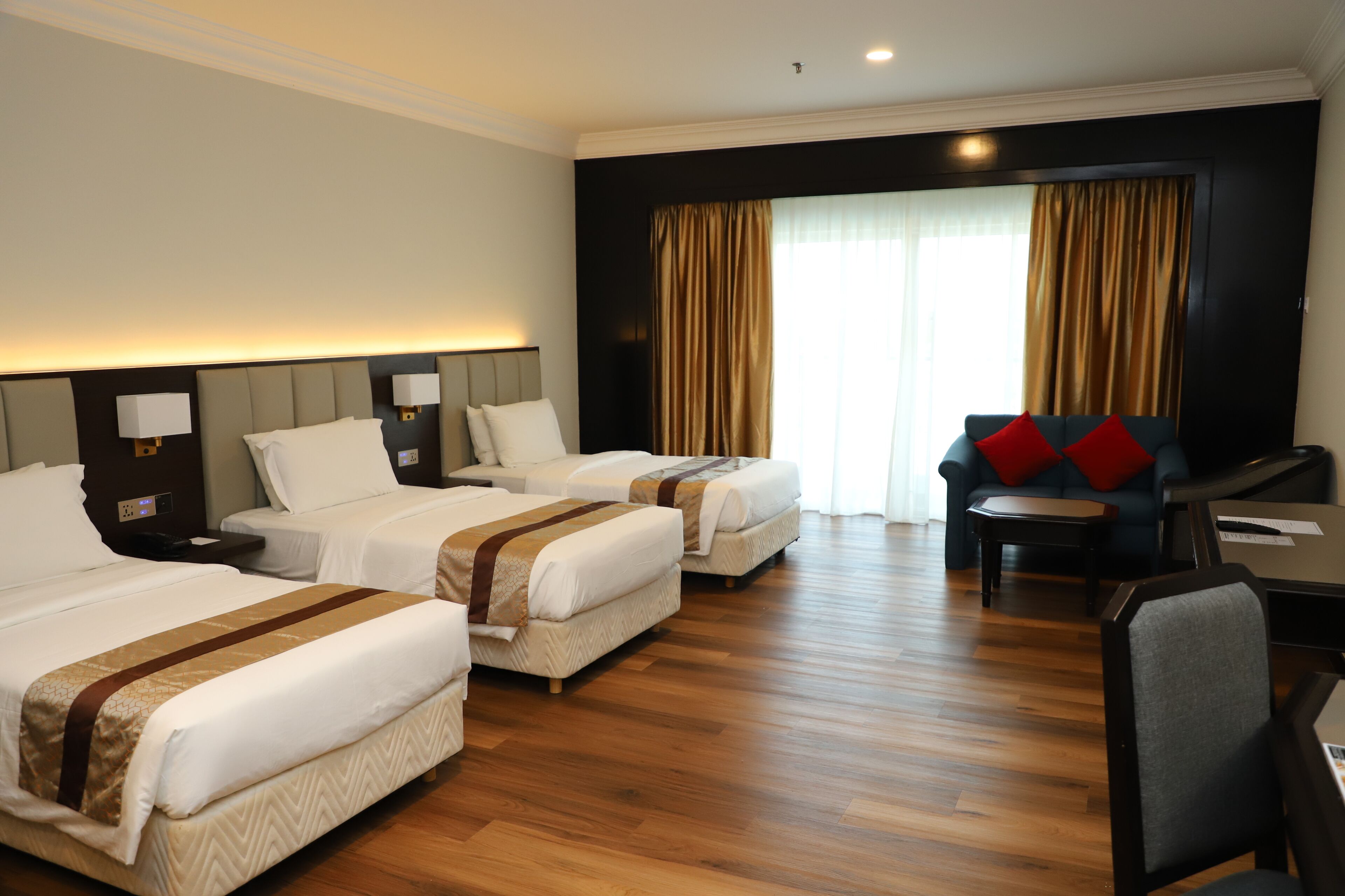A hotel room with two beds, a sofa, a desk, and a chair.