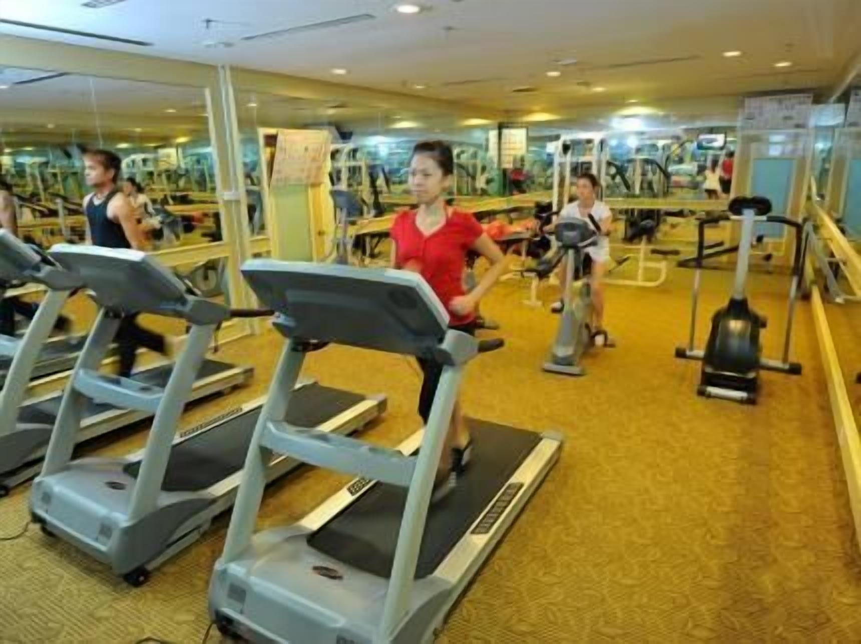 Un gimnasio con cintas de correr, bicicletas estáticas y elípticas.
