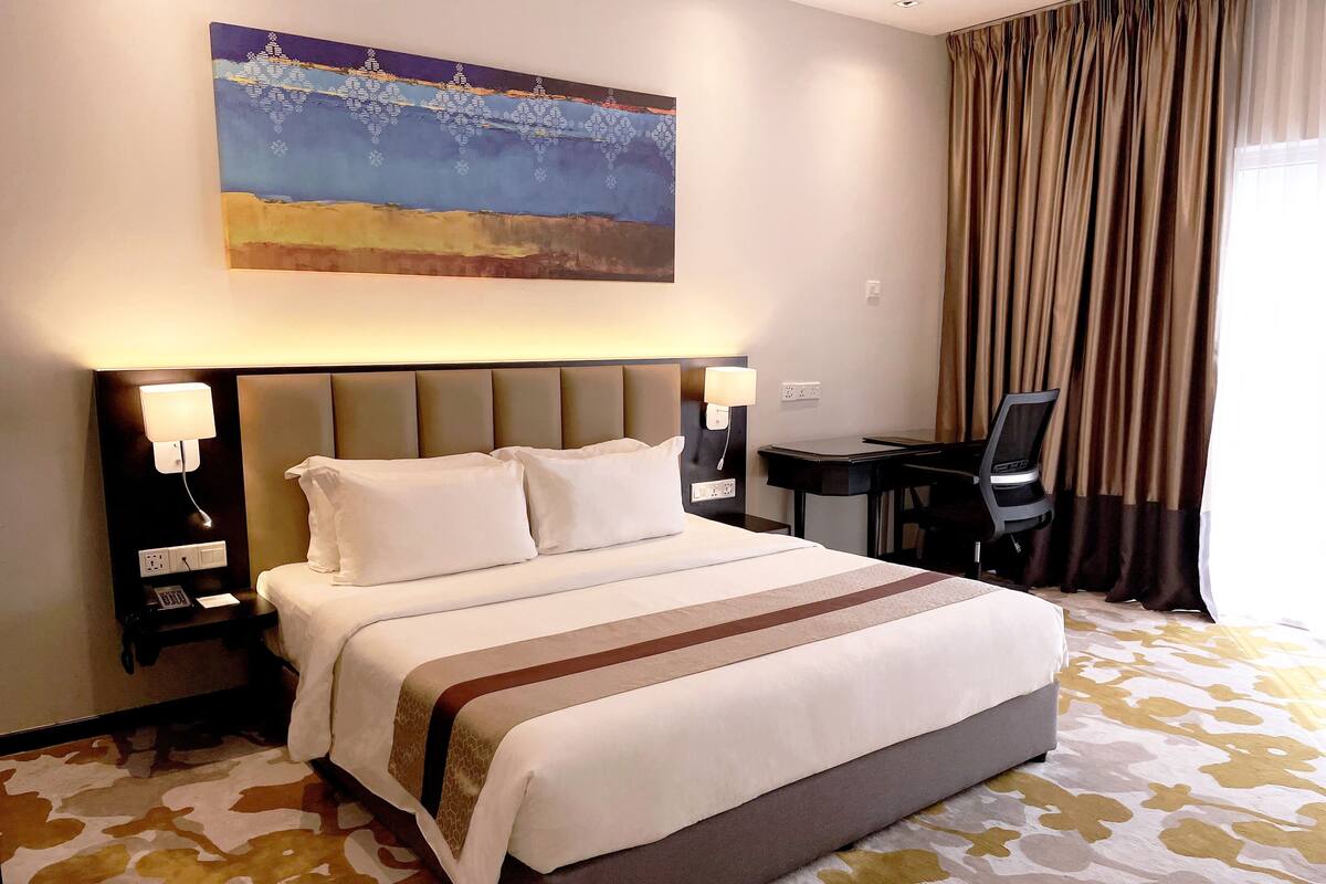 Een hotelkamer met een groot bed, twee nachtkastjes met lampen, een bureau en een stoel.