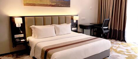 Una habitación de hotel con una cama grande, dos mesitas de noche con lámparas, un escritorio y una silla.