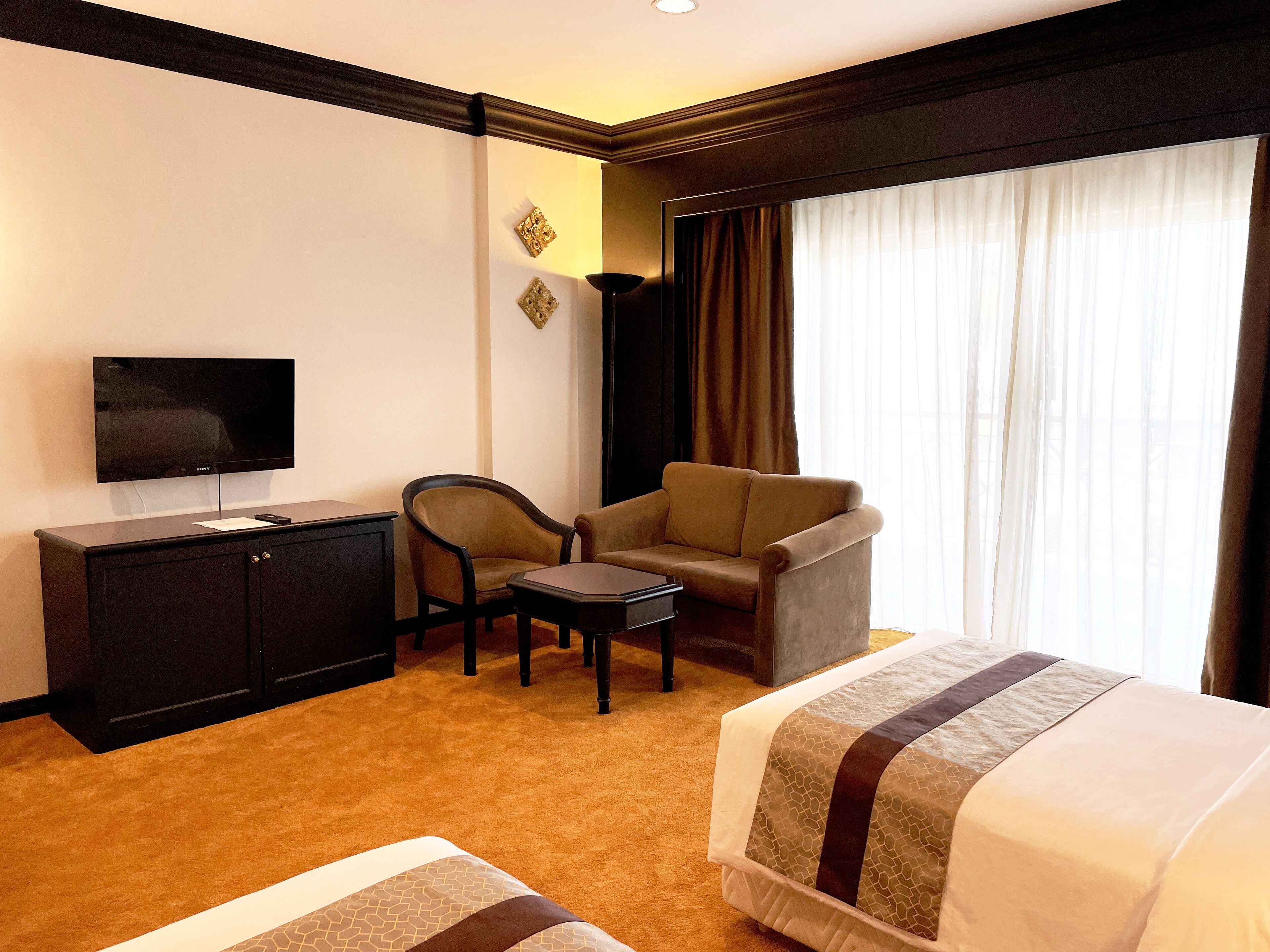 A hotel room with a bed, a sofa, a chair, a TV, and a desk.