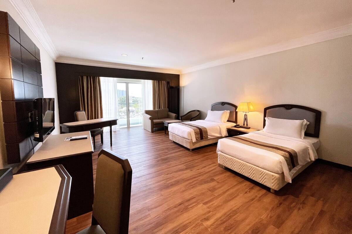 Een hotelkamer met twee bedden, een bureau, een stoel en een televisie.