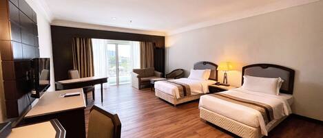 A hotel room with two beds, a desk, a chair, and a television.