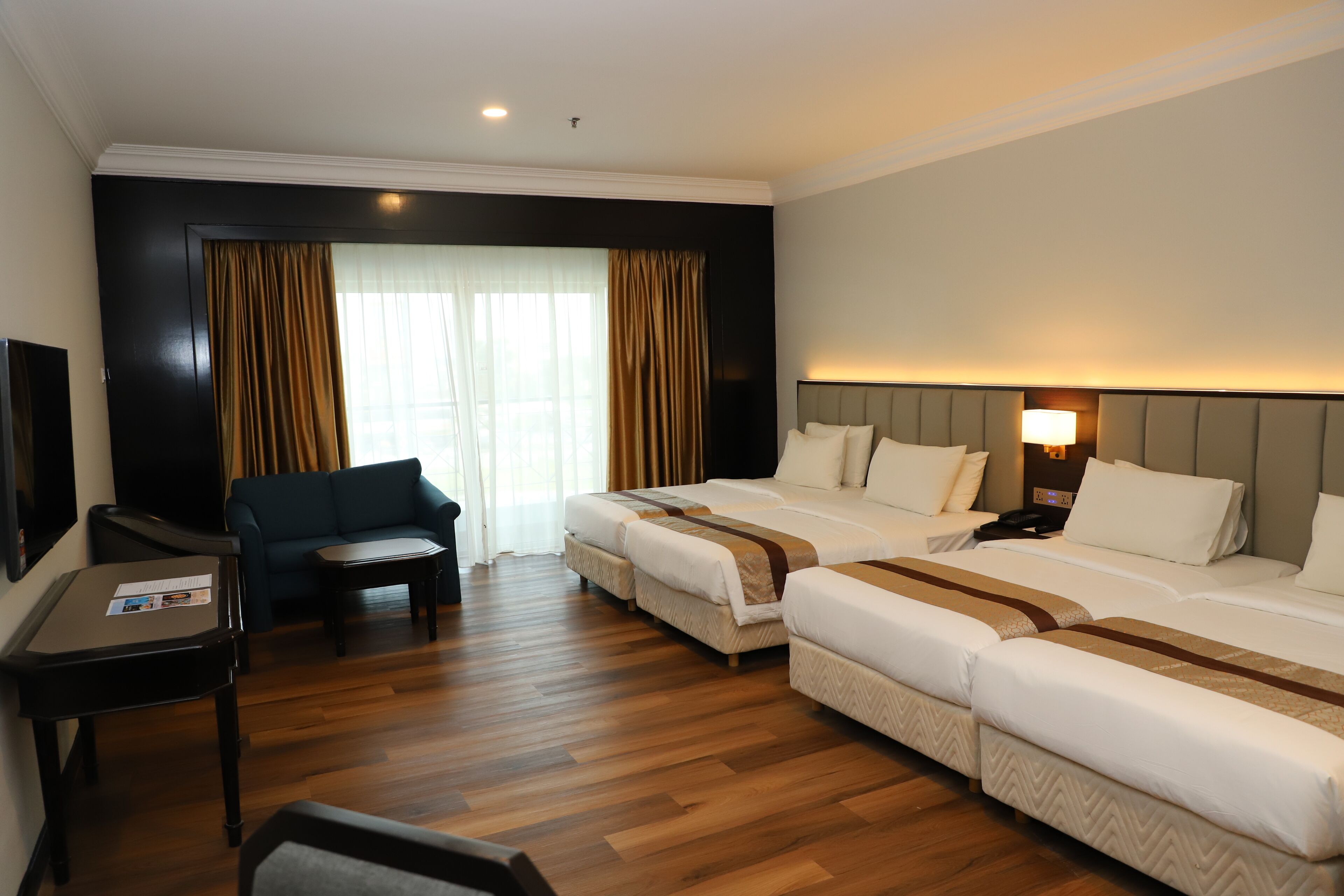 A hotel room with two beds, a sofa, a desk, and a TV.