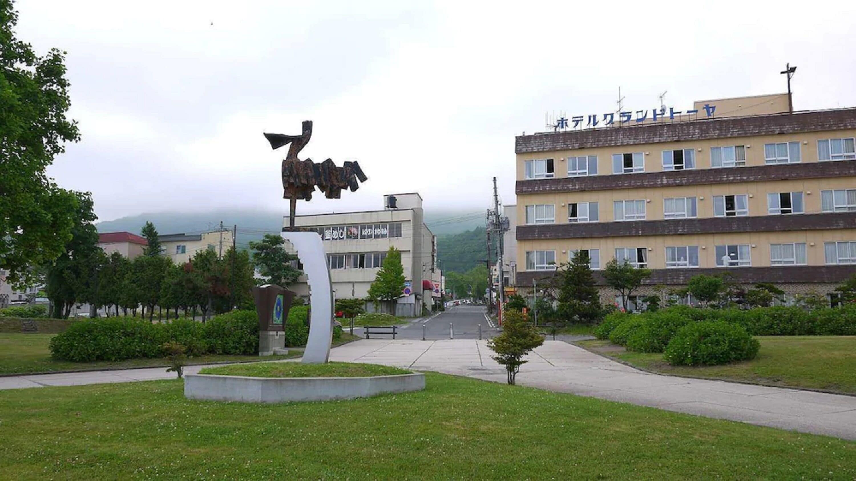 A building with multiple floors, a parking lot, and a statue in the foreground.