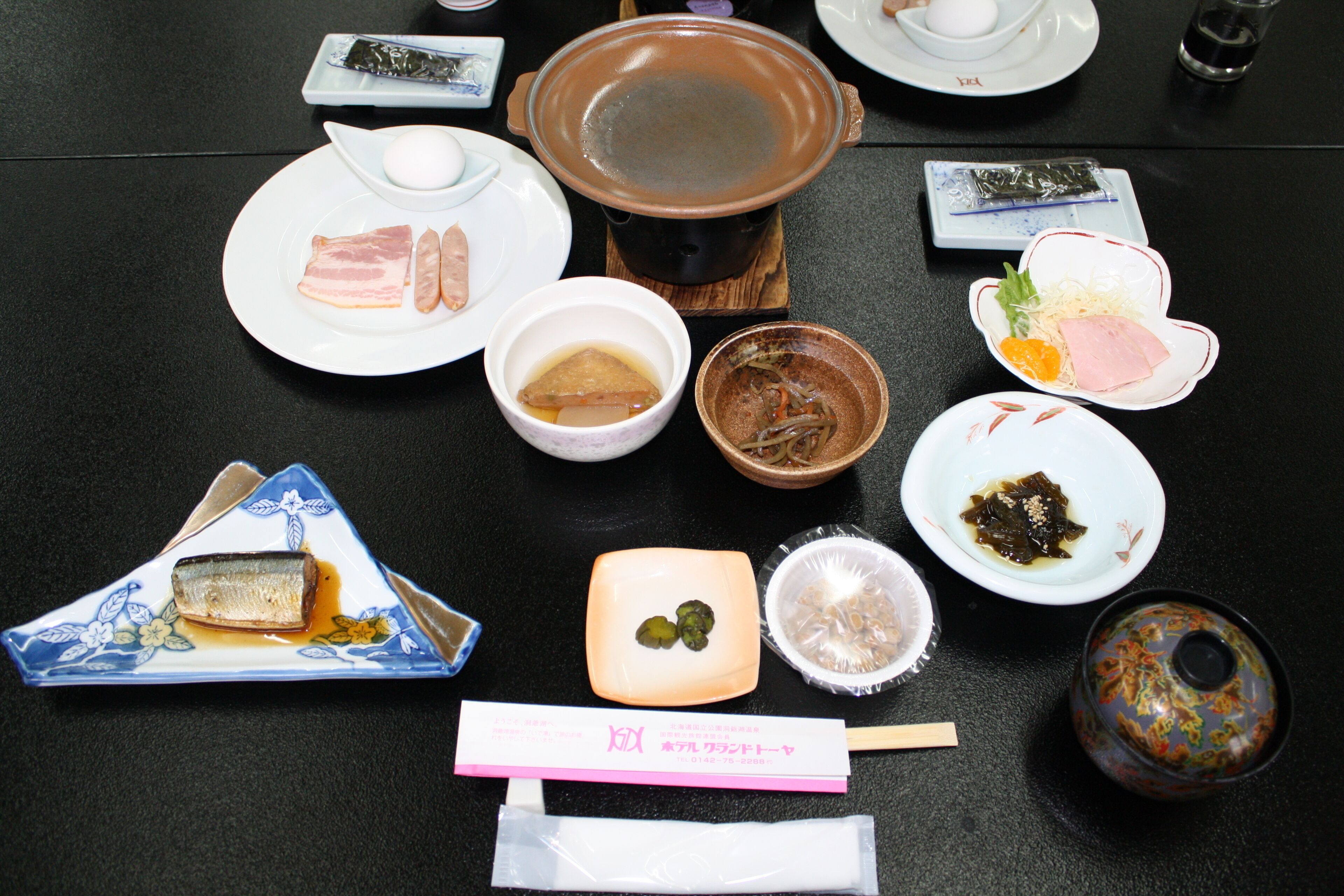 A table with various dishes, including a pot, bowls, plates, and chopsticks.