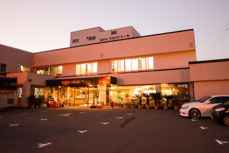 A hotel with a modern facade, a visible entrance, and a parking lot with cars.