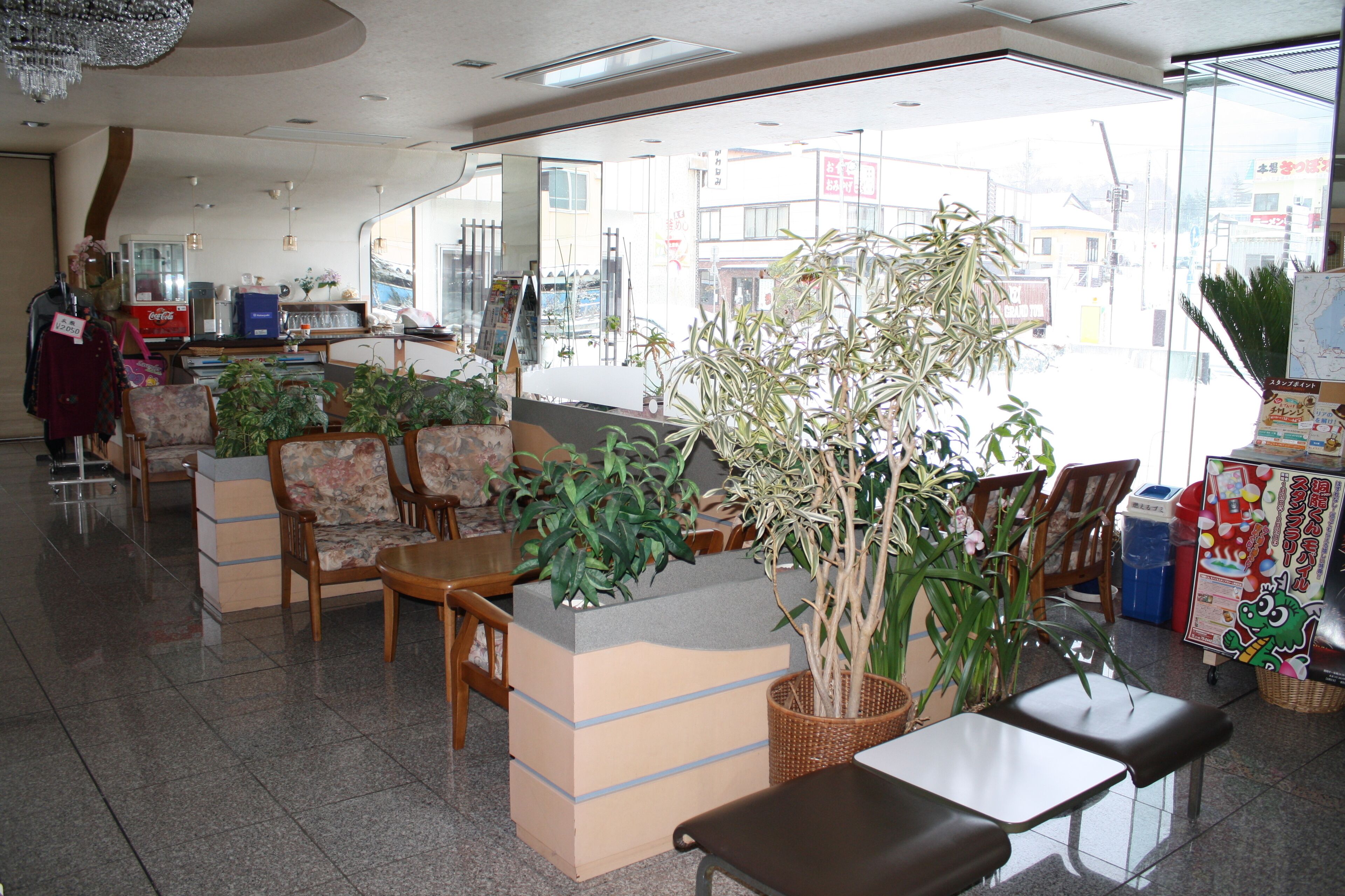 A hotel lobby with seating areas, a vending machine, and a large window offering a view of the street.