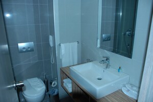 Un baño moderno con lavamanos, espejo y retrete blancos.