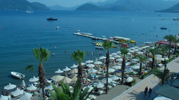 Une plage bordée de palmiers, avec des parasols et des bateaux.