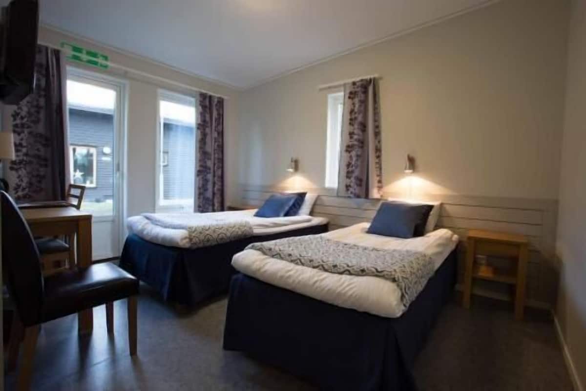 Een hotelkamer met twee bedden, een bureau en een stoel.