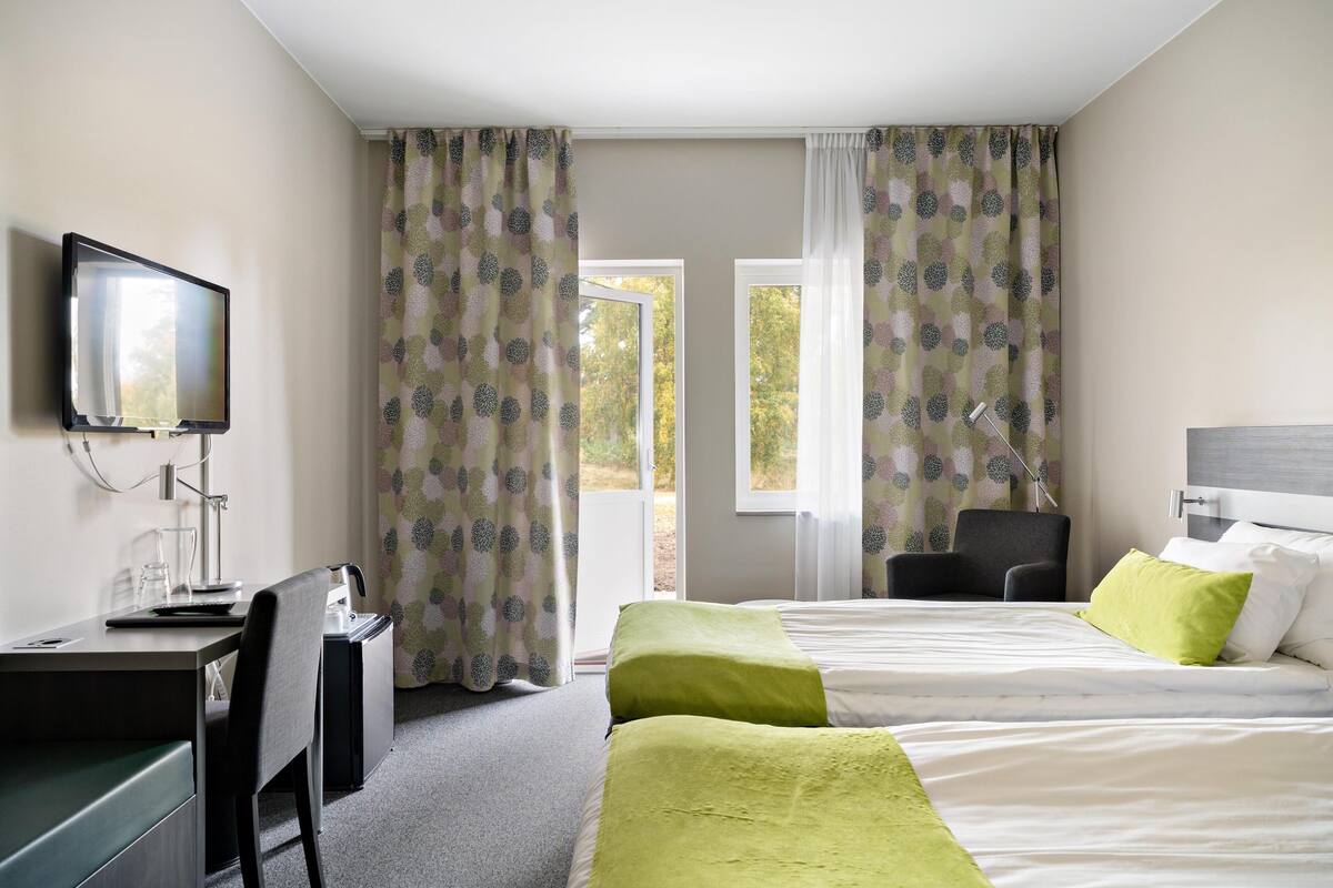 Een hotelkamer met een bureau, stoel, bed en een televisie.