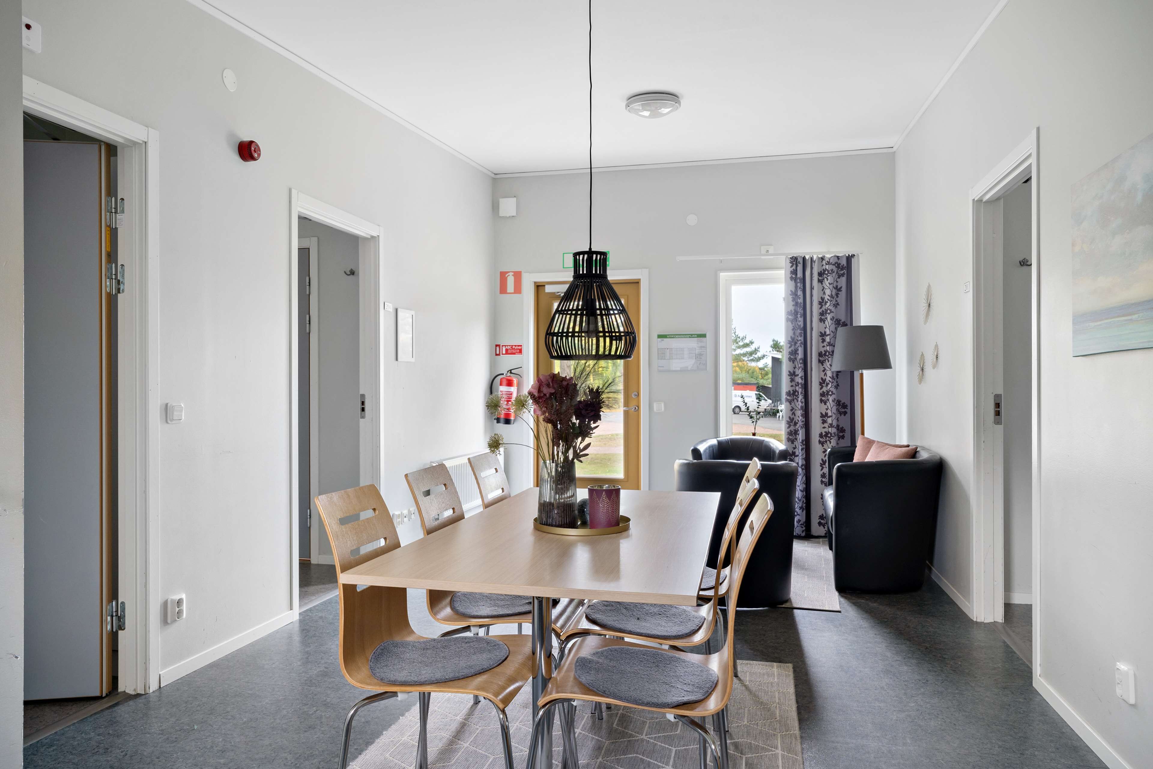 Un comedor moderno con una mesa y sillas de madera, una lámpara colgante y vistas al exterior.