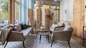 A cozy seating area with wicker furniture, a round table, and a view through large windows. - Tyleback Hotell & Konferens, BW Signature Collection (Halmstad)