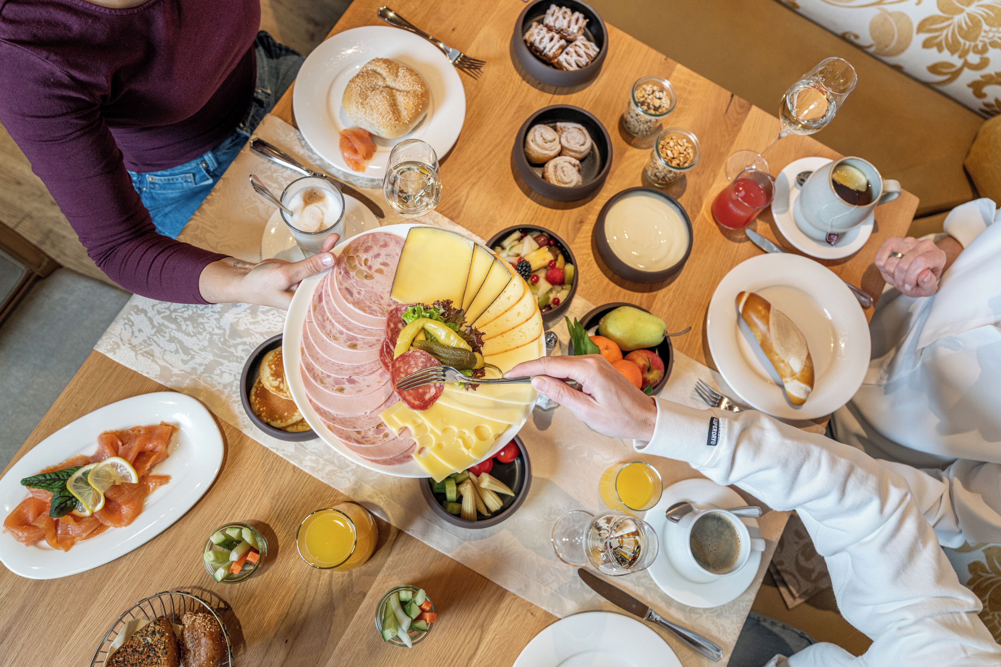 A breakfast setting with various dishes including cheese, ham, and fruits.