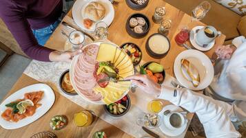 A breakfast setting with various dishes including cheese, ham, and fruits.