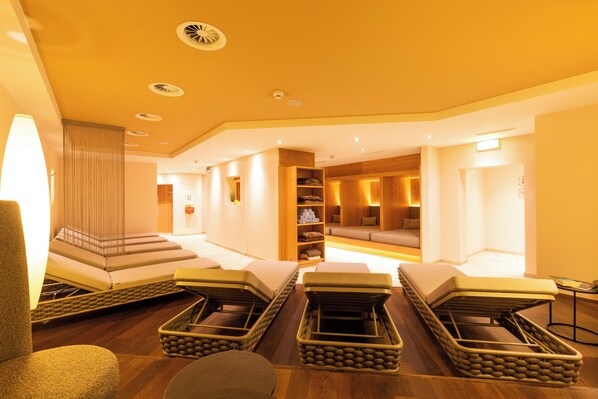 Un cuarto de spa con sillones de masaje, una recepción y una sala de estar con sofá y cojines.