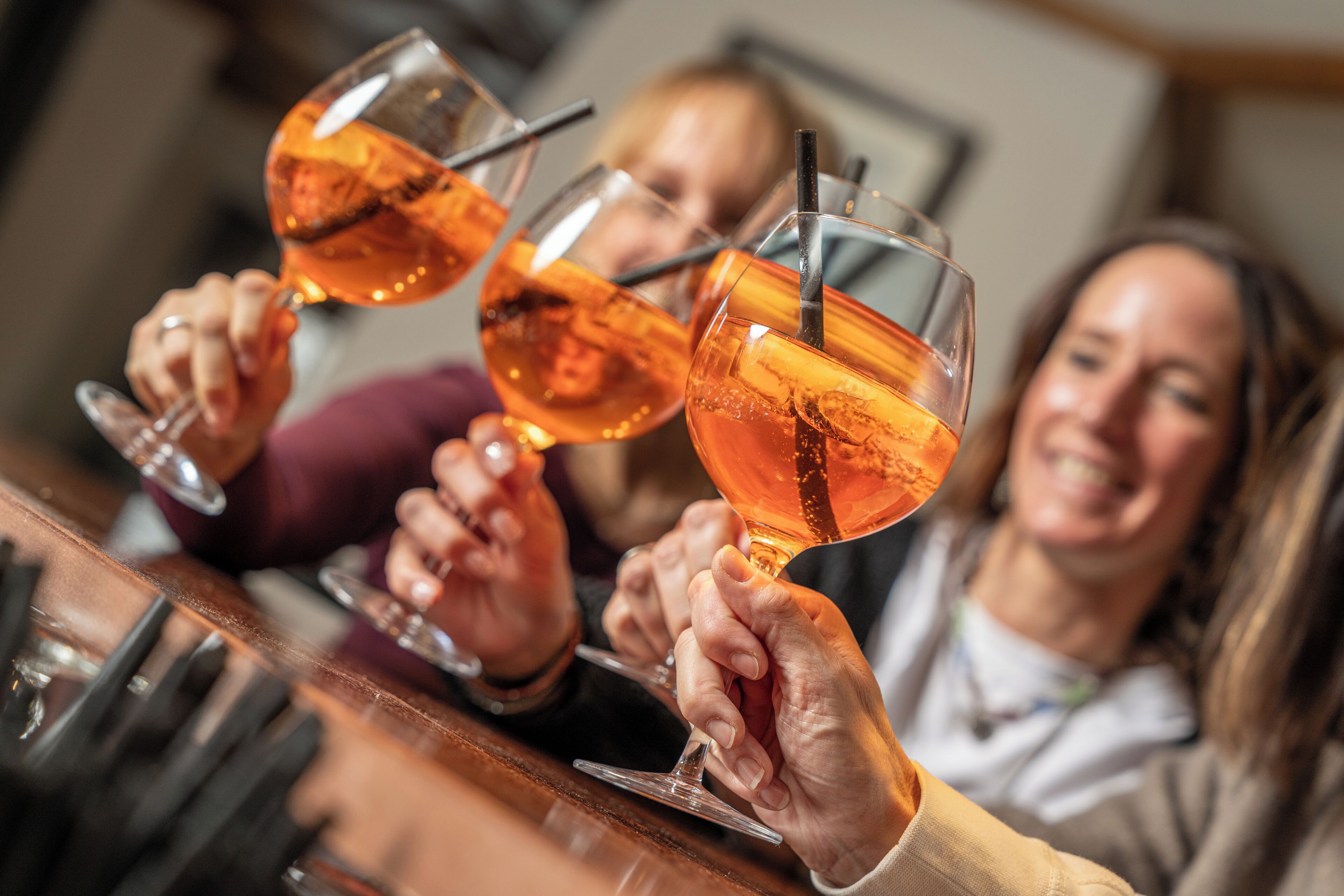 A group of people toasting with glasses of amber-colored beverages.