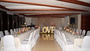 A long banquet table set for a formal event, flanked by rows of white chairs. - Hotel Principe (Chetumal)