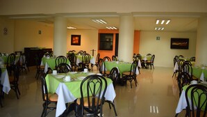 A dining area with tables set for meals, chairs, and a buffet counter. - Hotel Principe (Chetumal)