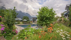 A garden with a pool, surrounded by lush greenery and flowers.