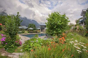 A garden with a pool, surrounded by lush greenery and flowers.