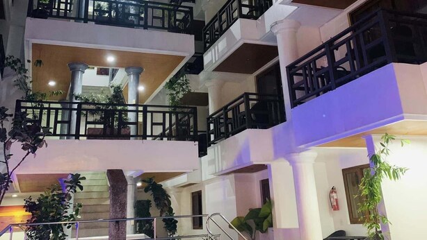Um hotel com vários andares, varandas, piscina e plantas dentro de casa.