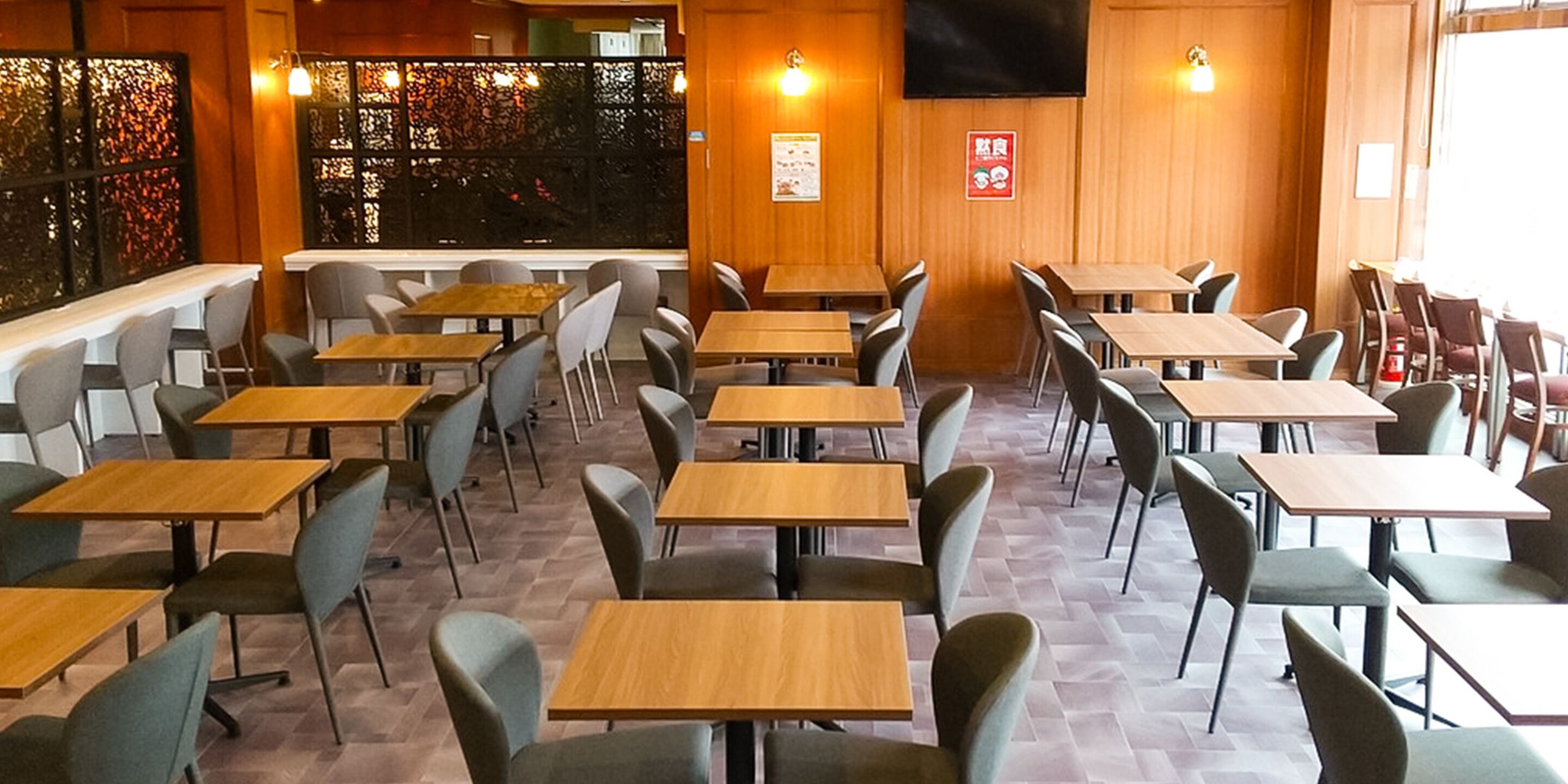 Ein Restaurantinneres mit mehreren Tischen und Stühlen, Holzboden und einer Wand mit einer Dekoration.