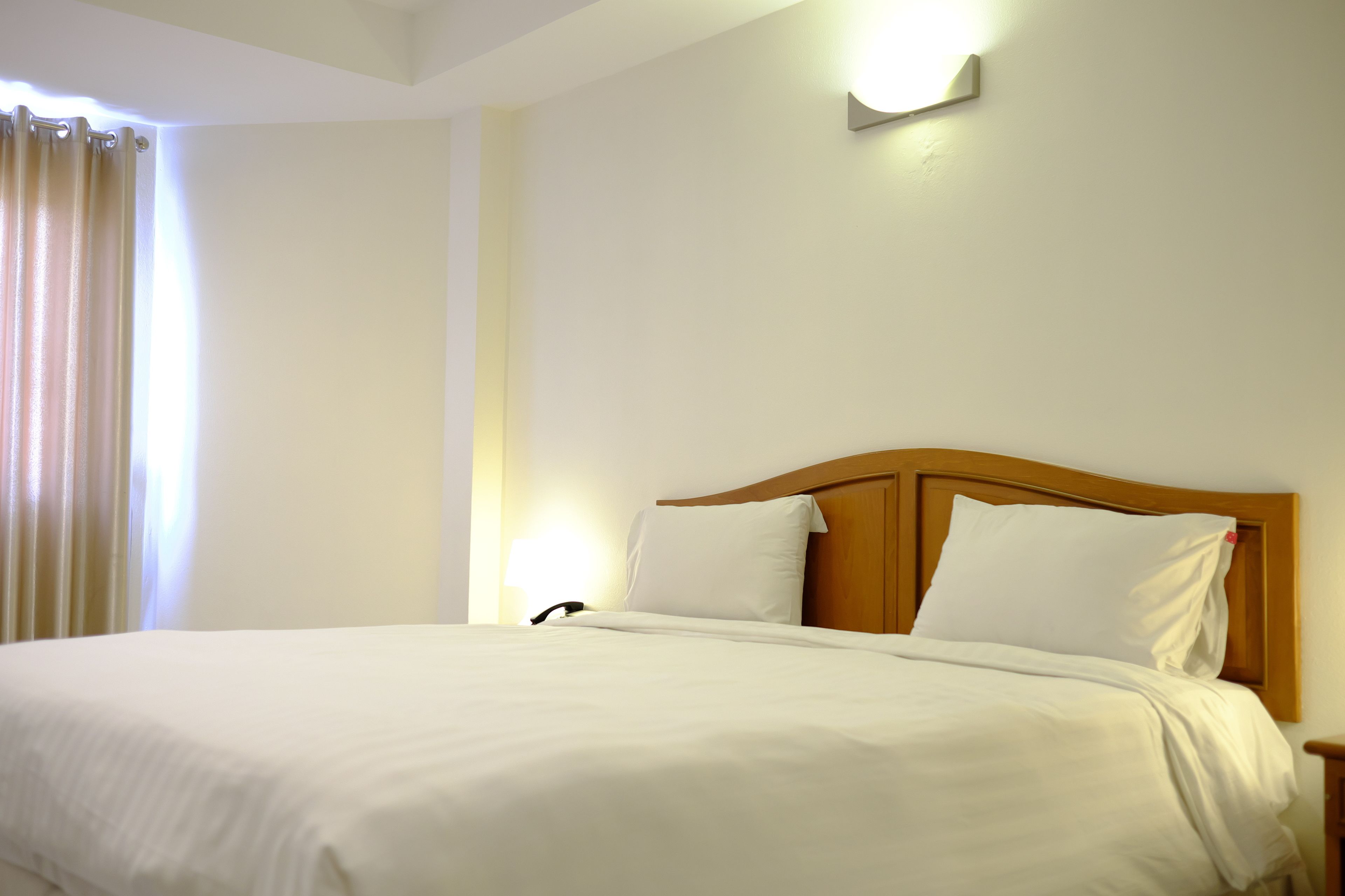 Une chambre d’hôtel avec un grand lit, une tête de lit en bois et une table de chevet.
